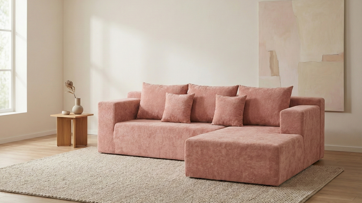 Pink sectional sofa in a room with a rug and abstract painting on the wall.